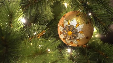 Greeting Season concept. Gimbal shot of ornaments on a Big Christmas tree with decorative light and falling snow in 4k (UHD)