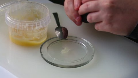 A man checks the quality of honey. He puts honey on a glass saucer and adds a few drops of iodine to it. The color has not changed, there is no starch in honey.