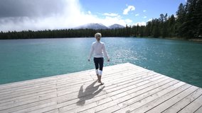 View of a young woman walking on lake pier and outstretching arms for freedom and body positive emotions. People enjoying nature in remote places concept
Shot in Jasper national park in Canada