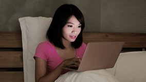 woman use notebook happily on the bed in the evening