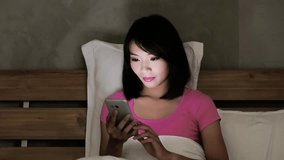 woman use phone happily on the bed in the evening