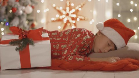 Santa Claus takes the gift over while the boy is sleeping