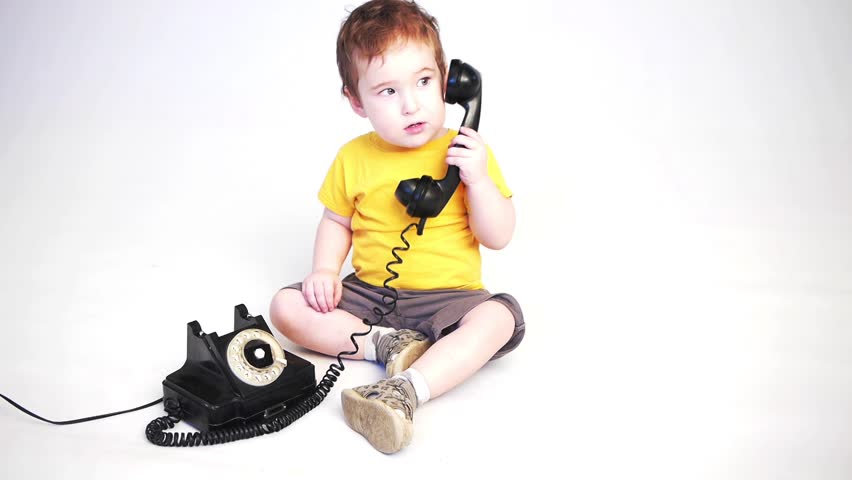 a kid playing with an old telephone