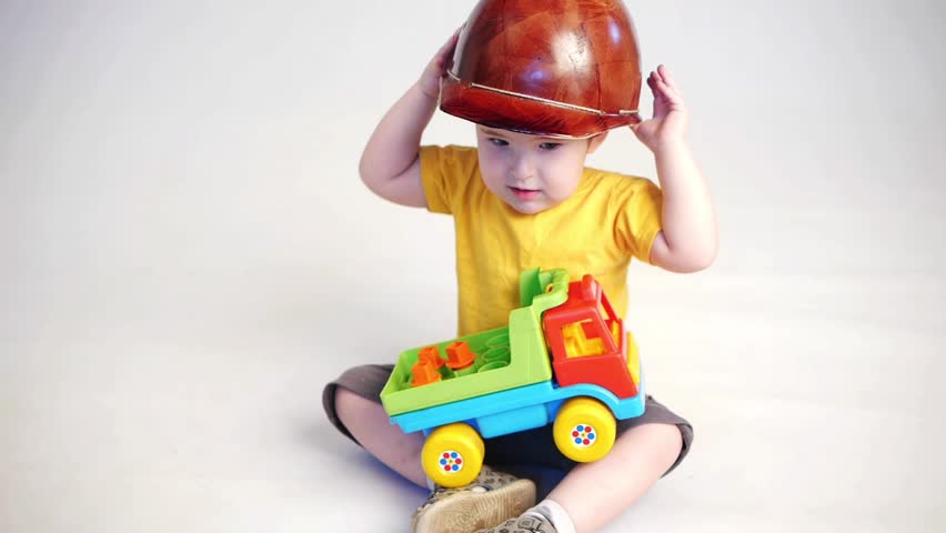 boy in builders hat play with truck