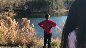 Great slow motion of kids approaching another kid in front of a lake and hugging