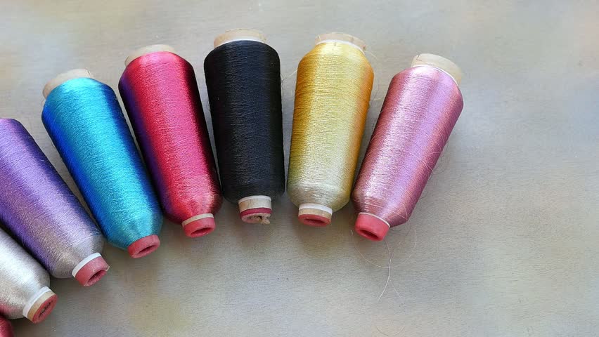 Sewing equipment or material background footage - multi color spool of threads on wooden table 