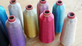 Sewing equipment or material background footage - multi color spool of threads on wooden table 