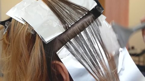 Stylist hairdresser makes hair coloring, blonding, coloring hair roots.