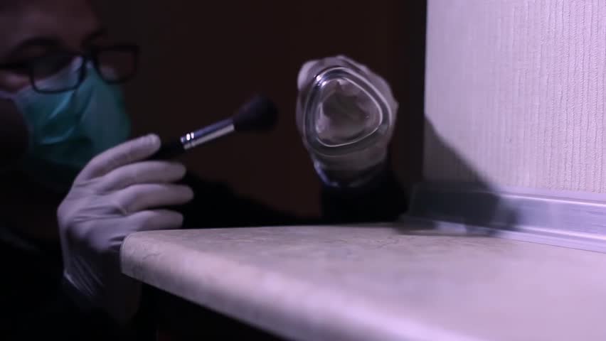 CSI Expert at crime scene packing glass with fingerprints