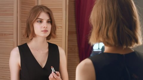 Young attractive woman make up her lips in front of the mirror