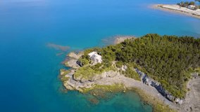 Aerial birds eye view video taken by drone of small island with lighthouse and rocky seascape