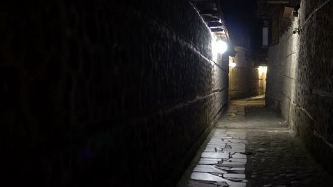 Mysterious narrow alley with stone pavement lanterns at night
