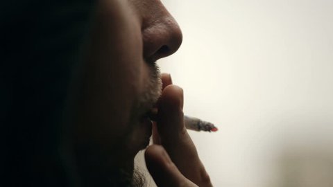 Closeup shot of a man's face who smoking a cigarette.
