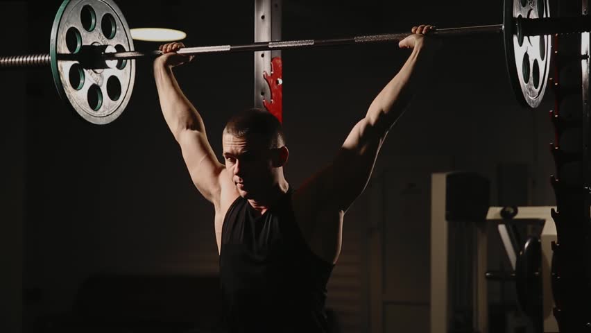 Young muscular man at the gym performing squats.