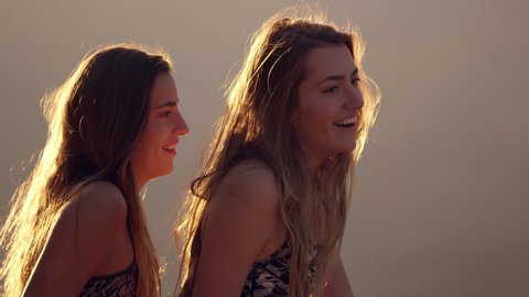 Twin teenagers talking and laughing with each other as they look and point in the distance.