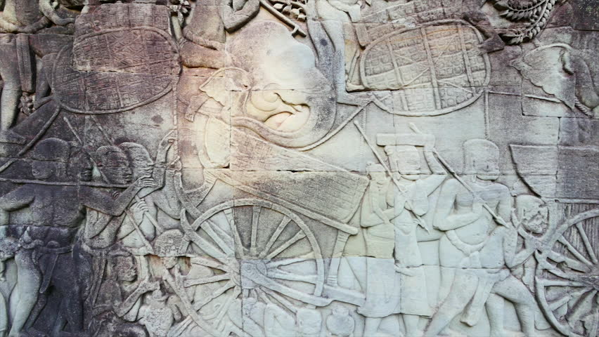 A panning shot to the left of a wall with engraving of people.