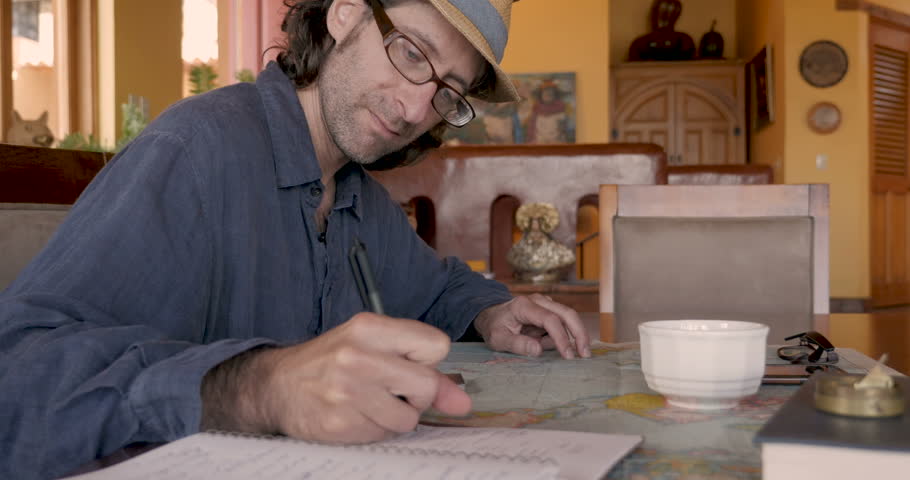 Attractive man planning his vacation using a map and notebook - dolly shot
