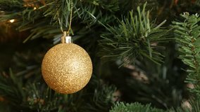 Glittering gold bauble hanged on the branch 4K 2160p 30fps UltraHD footage - Sparkling gold color ornament on Christmas tree 3840X2160 UHD video
