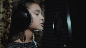 Singer child is training to make music in professional studio. Song production process. Talented kids. Track recording.
