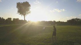 Black dress girl posing in the golf field near big tree. Sunset light