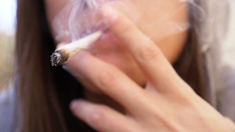 cannabis, marijuana, light drugs: woman smokes a joint,close up