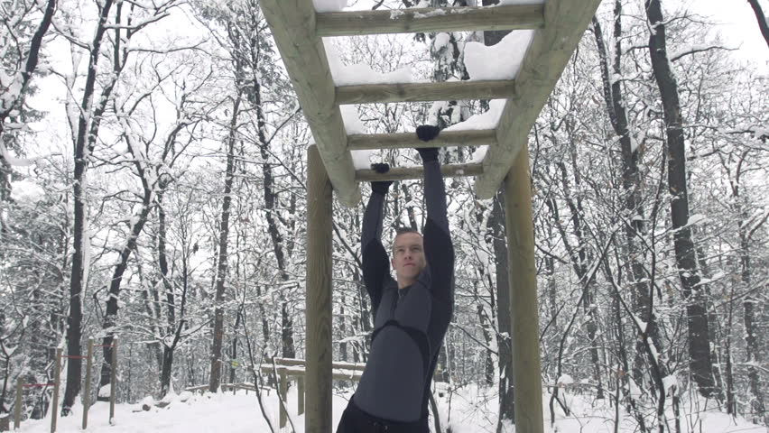 Slow Motion Of Young Sportsman Training On Horizontal Ladder In Snowy Forrest.