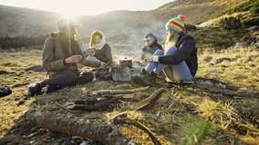 Young people preparing meal over fire in mountains