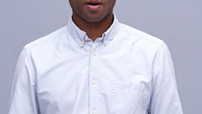 Cropped view of Young african man fastens his shirt over gray background