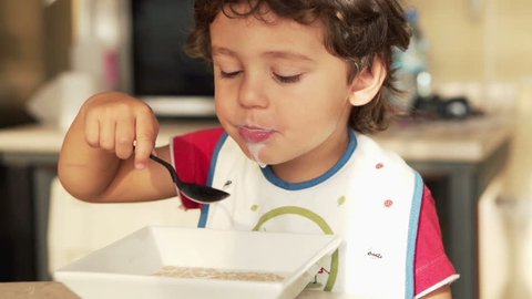 Cute kid eating milk with cereals
