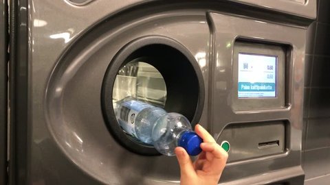 Plastic Bottle recycling pawn machine. Hand feeding bottles to machine which pays every bottles and cans. 7th December 2017. Finland, Espoo, Olari. 