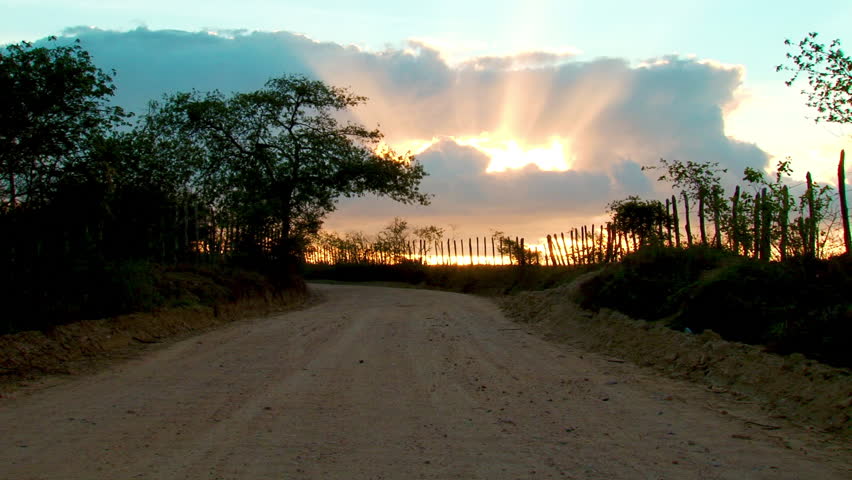 Rays of sunlight breach through the clouds over a dirt road ALTERNATIVE VERSION