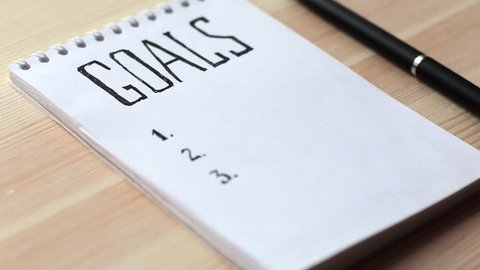 Goals concept. Notebook with goals list on wooden table. Motivation strategy write idea success solution concept.