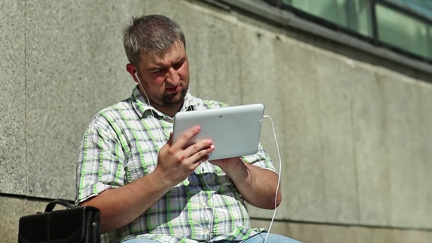 Man uses tablet computer, holds in hand tablet pc. Businessman works with tablet computer
