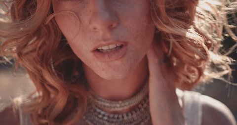 Close-up of young woman with freckles in boho style wearing silver jewelry outdoors in summer