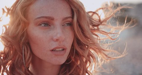 Close-up of redhead woman with green eyes and freckles relaxing at the beach in summer