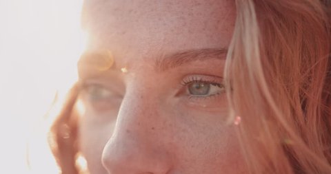 Close-up of redhead woman with green eyes and freckles looking at view in summer