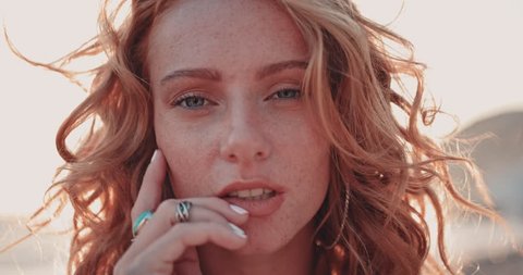 Close-up of young redhead hippie woman with freckles relaxing at the beach in summer