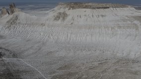 Aerial video of vast lands of dry desert lands with sands and high stone cliffs, footage of solid monolith from stones and chalk mineral in Gobi desert 