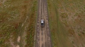 Aerial video of rented car driving with high speed on off road in desert wild lands exploring environment and scenery.