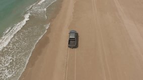 Bird’s view of rented car with tourists enjoying environment in summer time during extreme ride along seashore.Video of leased automobile driving on dry coastline of island during expedition