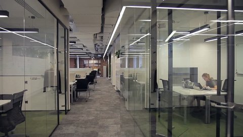 Business center with offices with glass partitions, in which employees work. Representations of different companies and companies are located in a spacious, bright and modern room.