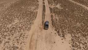Footage of extreme lovers driving on jeep in wild landscape of desert.Aerial footage of travelers having expeditions by rented automobile bashing on safari trip