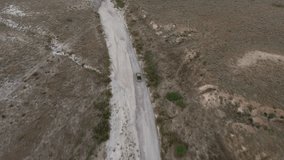 Aerial video of off road in wild natural environment of desert in america with rental automobile.Footage of car driving on dry lands crossing sandy hills during rally competition