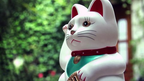 White Lucky Cat, Maneki-neko, on Green Background. Close-Up. Zoom In. 