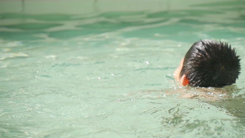 Asian boy relaxing in pool with sun light, slow motion