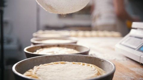Cook sifts flour and sugar decorating pies in the bakery