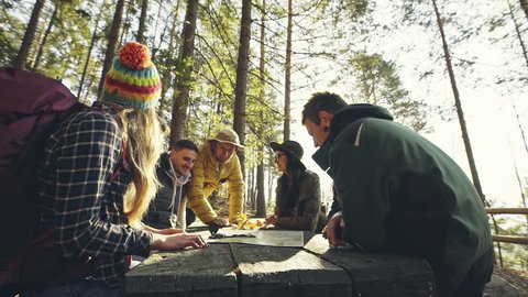 Group of friends reading map at wooden table