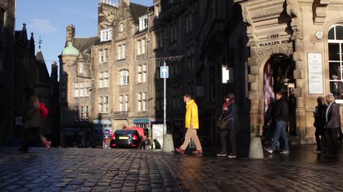 EDINBURGH, UK - 4 DEC, 2017: Tourists walk along the cobbled street of the Royal Mile on a cold but sunny Autumn day