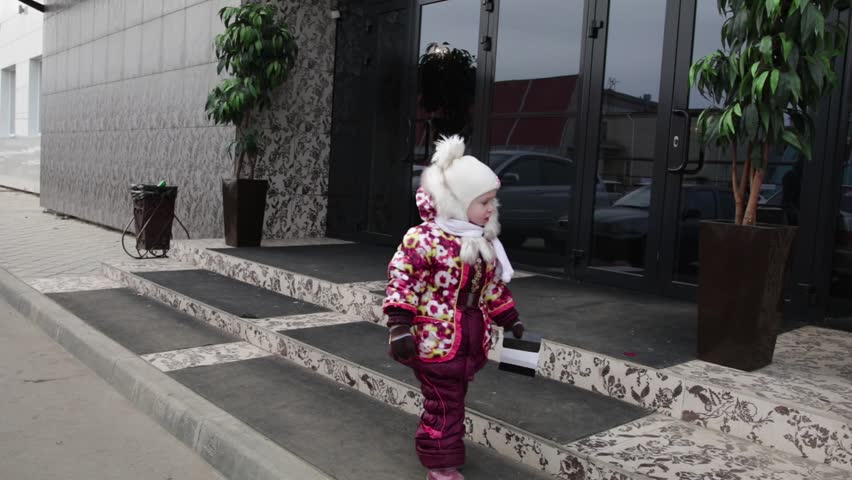 A small child in the street throws a paper