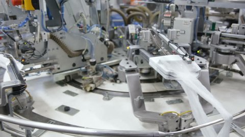Robotic Arm in Action. Hosiery Manufacturing. Robotic arm working on factory assembly line.Industrial Mechatronics. Automated Production in Factory. Tights Manufacturing Workshop. Industrial Robot.